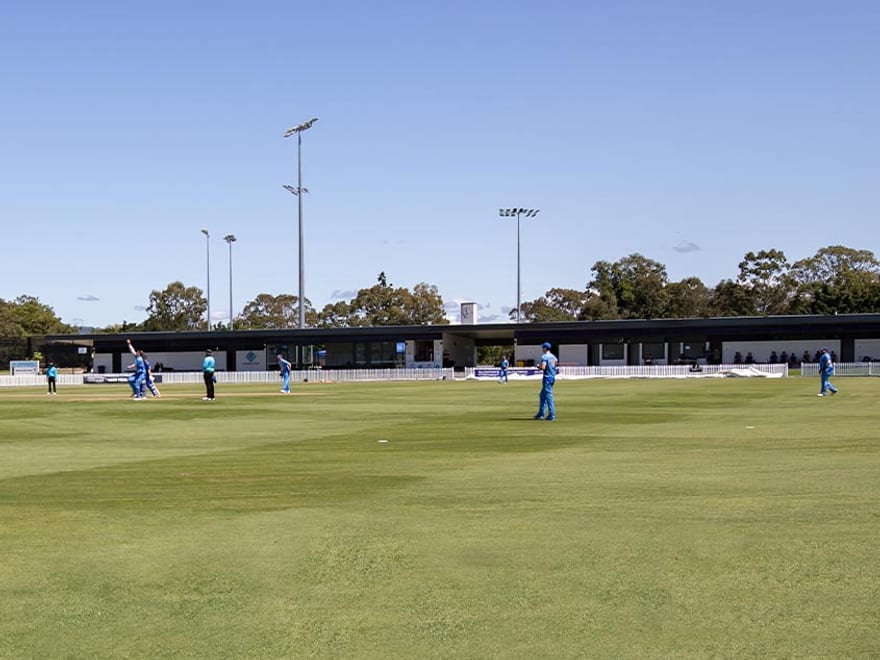 Shaw Park, Kedron — a turf oval mid-match under a clear Brisbane sky.